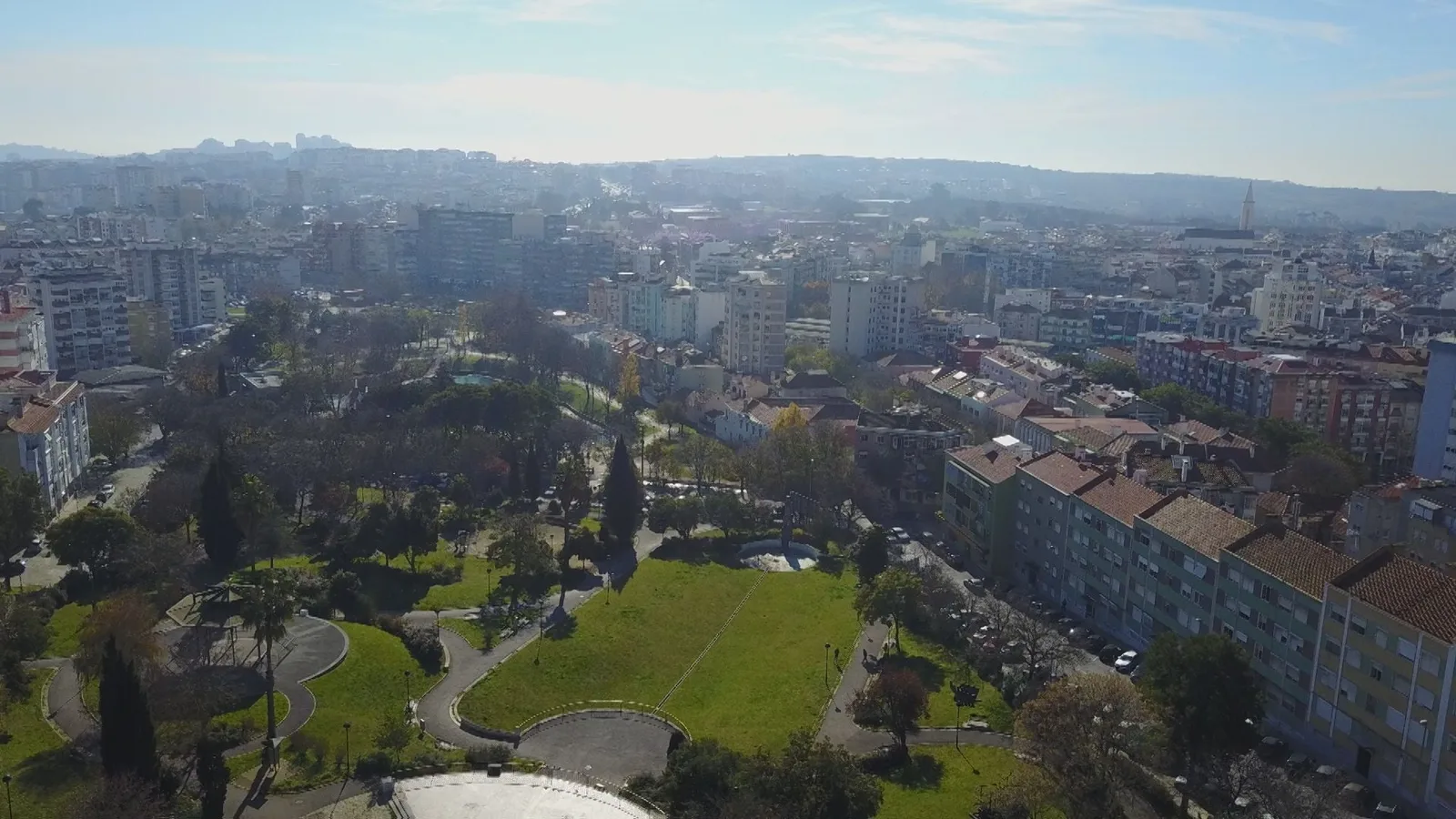 Panorama do centro da Amadora, com edifícios residenciais e um parque urbano em primeiro plano.
