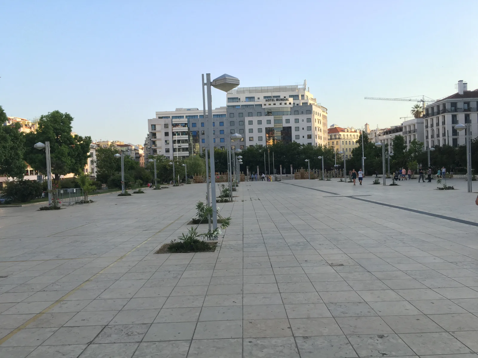 Perspetiva ampla da Praça Martim Moniz ao entardecer, com pessoas no espaço público e edifícios em fundo.