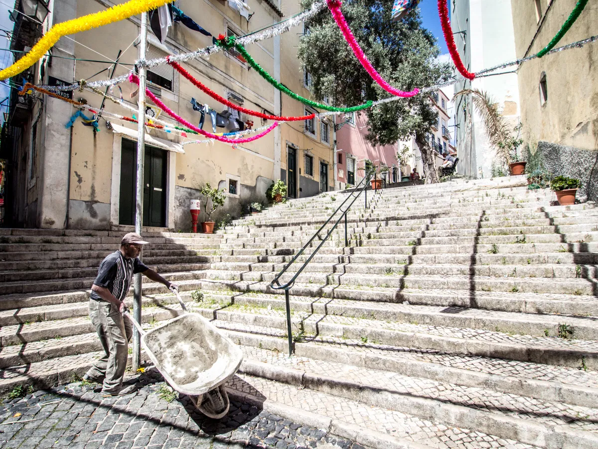 Homem transporta um carrinho de obra pelas escadas de uma rua residencial de Alfama, em julho de 2014.