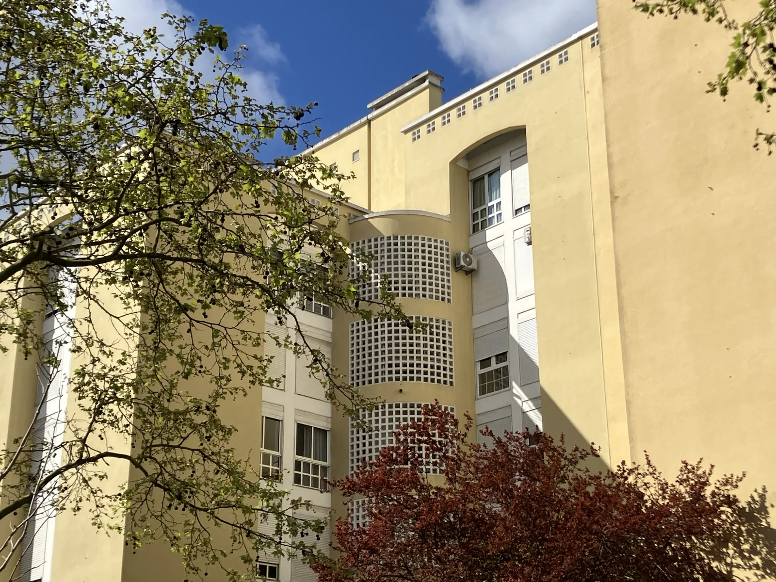 Edifícios residenciais amarelos, com varandas e árvores, na Rua Hermano Neves, em Telheiras, Lisboa.