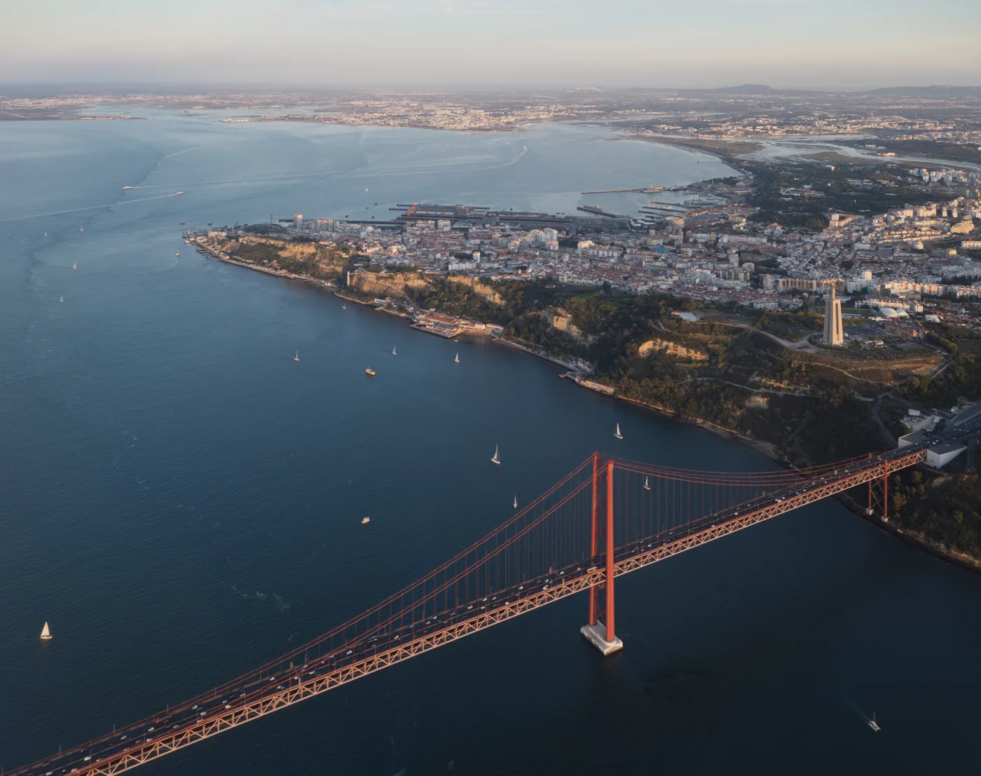 Ponte 25 de Abril e as margens de Almada e Lisboa, vistas de avião. Fotografia documental de contexto, sem identificar capacidade edificável.