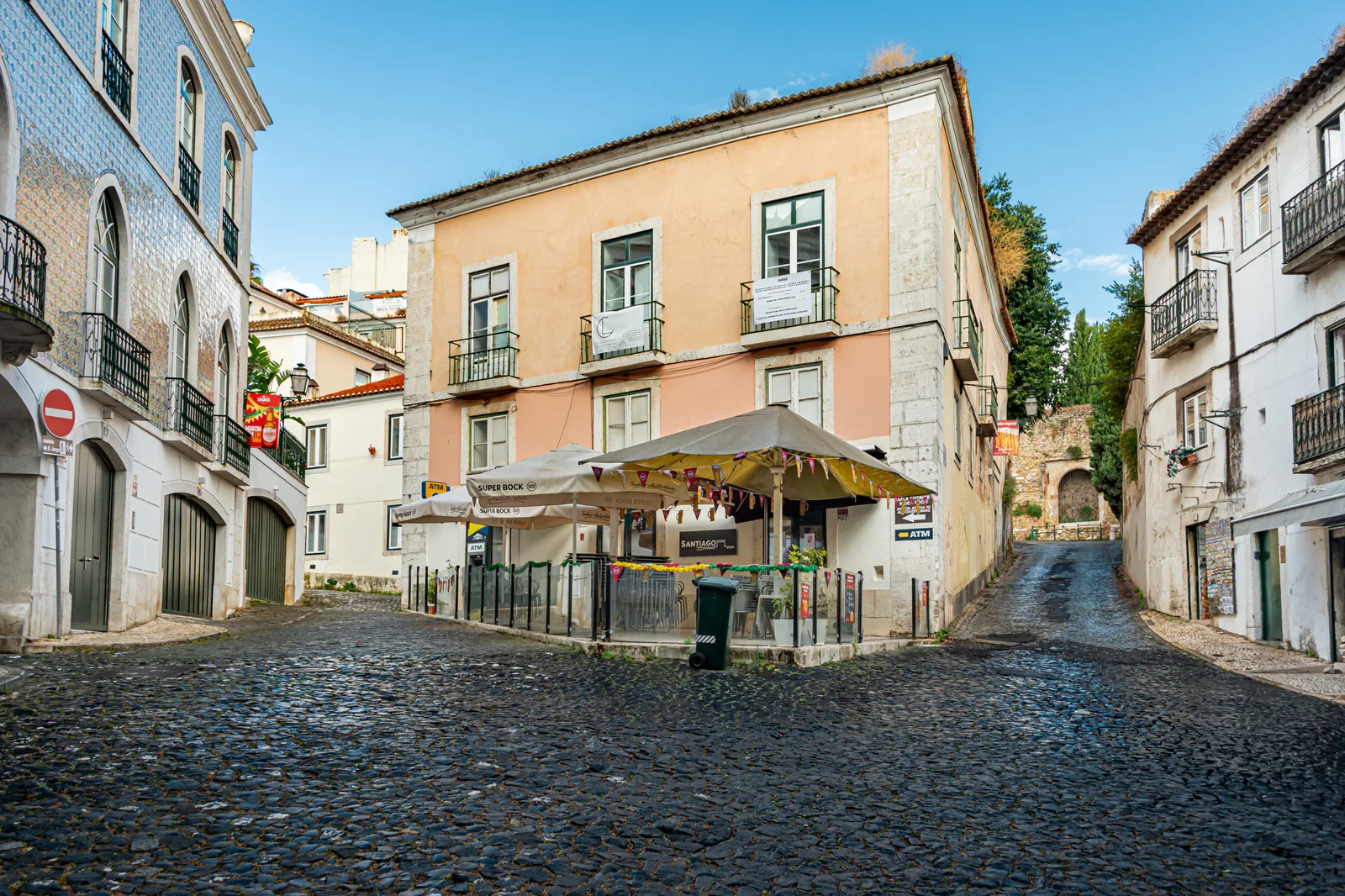 Rua e fachadas em Alfama, com esplanada sobre o pavimento de calçada.