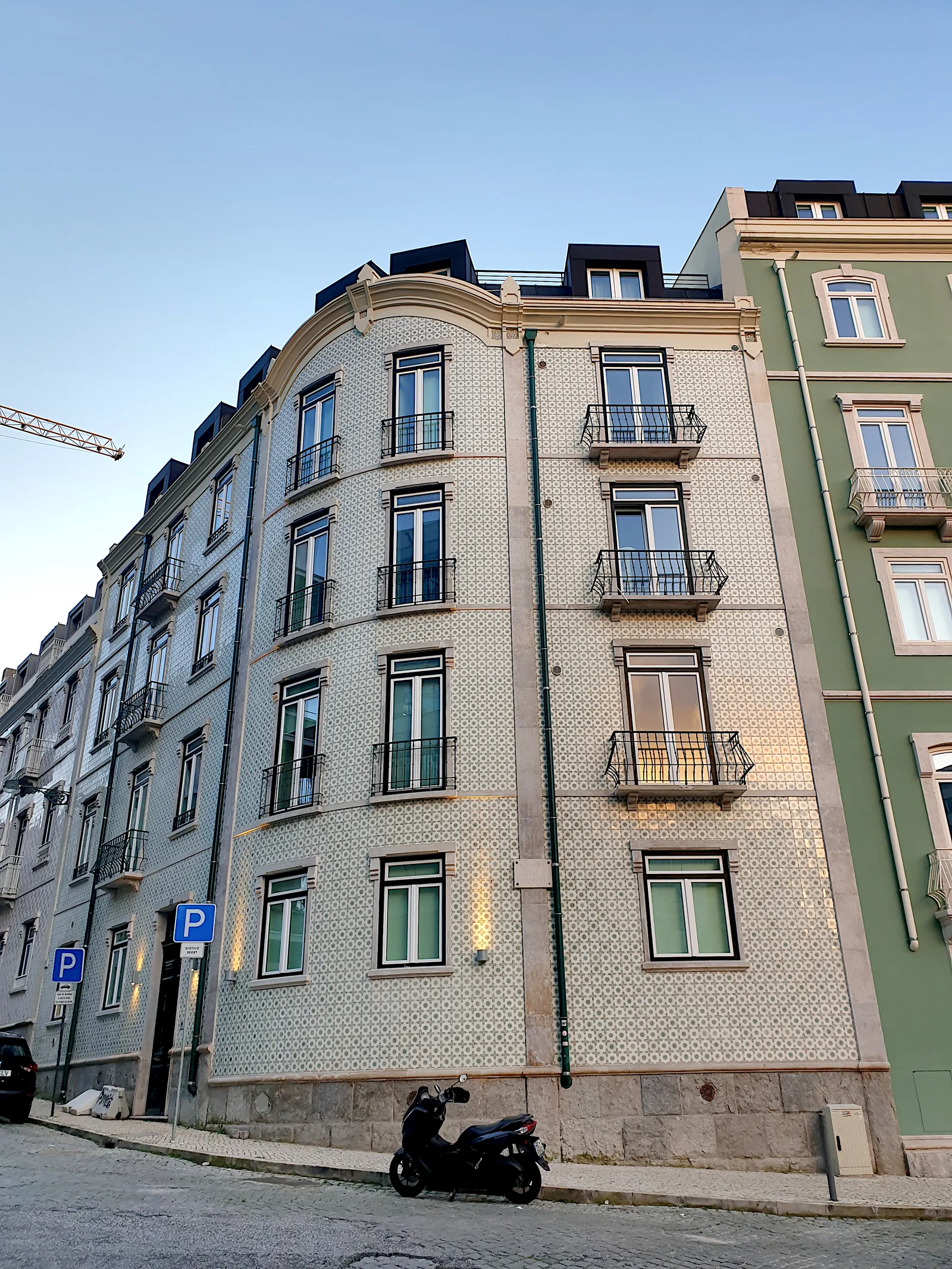 Prédio de esquina em Lisboa com fachada de azulejos, janelas e varandas.